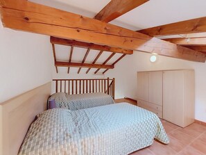 Ein Schlafzimmer mit Holzboden, einem Bett mit kariertem Überwurf und einem Kleiderschrank.
