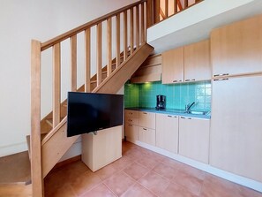 Eine Küche mit Holzausstattung, einer gefliesten Spritzschutzwand und einem an der Wand befestigten Flachbildfernseher.