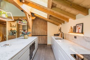 Eine moderne Küche mit einer zentralen Kochinsel, Holzbalken und einer hängenden Leuchte.
