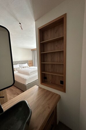 Un dormitorio con una cama, una estantería de madera y un escritorio.