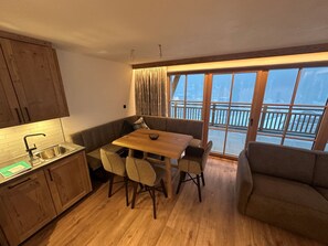 Cocina compacta con comedor, armarios de madera y vistas amplias por ventanas grandes.