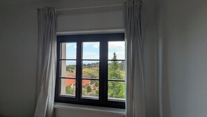A room with a window, curtains, and a view of buildings and trees. - Villa Da Vele - Between Volcano and the sea (Nicolosi)
