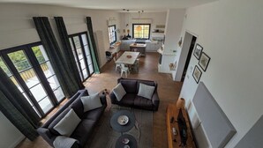 A spacious living area with a sofa, coffee table, and a dining table with chairs. There is a kitchen area with a stove and cabinets. - Villa Da Vele - Between Volcano and the sea (Nicolosi)