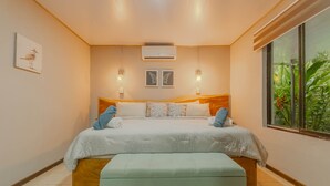 A bedroom with a bed, bedside lamps, an air conditioner, and a window with a view of greenery. - Uvita vacation rental with private pool, rancho lounge, and lush garden just minutes from the beach. (Uvita)