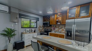 A modern kitchen with a refrigerator, microwave, and a coffee maker. - Uvita vacation rental with private pool, rancho lounge, and lush garden just minutes from the beach. (Uvita)