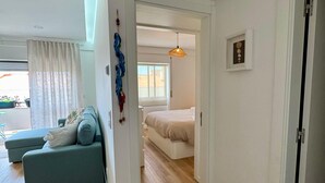 Ein modernes Wohnzimmer mit Sofa, Essbereich und Schlafzimmer mit Bett und Pendelleuchte.