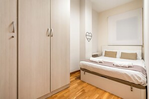 Ein Schlafzimmer mit einem Bett, einem Holzschrank und einer herzförmigen Dekoration an der Wand.