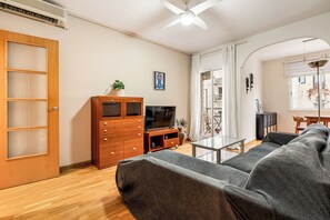 A living room with a sofa, TV, wooden cabinet, and a dining area with a table and chairs. - Poble Sec Flat · 2 Balconies · A/C · 4 Guests · Near Montjuïc (Barcelona)