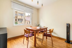 Ein Essbereich mit Holztisch und Stühlen, einem Fenster mit Jalousien und einer Heizung.