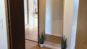 Ein Flur mit Holzboden, einem großen Spiegel und zwei Zimmerpflanzen.