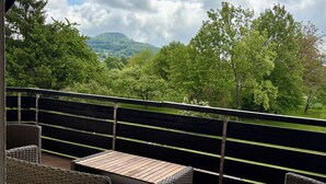Ein Balkon mit Korbmöbeln und Blick auf eine grüne Landschaft.