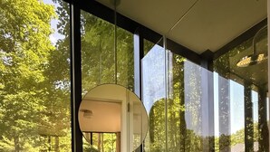 Een moderne badkamer met een groot raam, een ronde spiegel en een beige wasbak.