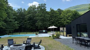 Un giardino sul retro con piscina, area relax esterna e un edificio moderno.