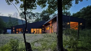 Un edificio moderno con ampie finestre e facciata in legno, immerso nel verde.