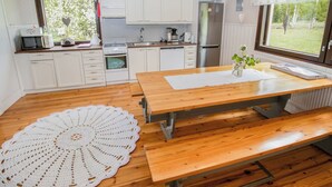 Una cocina moderna con armarios blancos, una mesa de madera y un amplio ventanal.