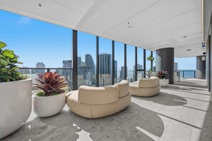 A modern indoor space with large windows, a seating area with sofas, and potted plants. - CASSA CASINO TOWER 2 - Brand New Premium Residence Managed by The Cassa (Broadbeach)