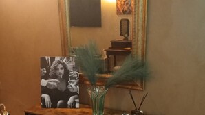A wooden console with a mirror, a vase with green foliage, and a remote control. - Blossom Rue De Nava B&B (Reggio Calabria)