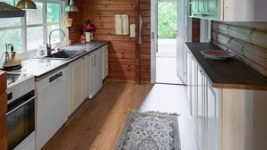 Una cocina con paredes de madera, un lavamanos, armarios y una ventana.