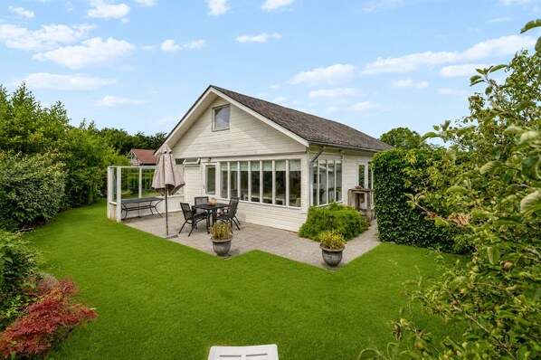 Een huis met een terras, een eethoek en een wintertuin.