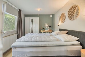 Een slaapkamer met een bed, bureau, stoel en garderobe.