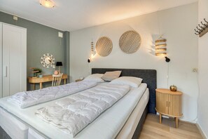 Ein Schlafzimmer mit einem großen Bett, Nachttischen, einem Schreibtisch und dekorativer Wandbeleuchtung.