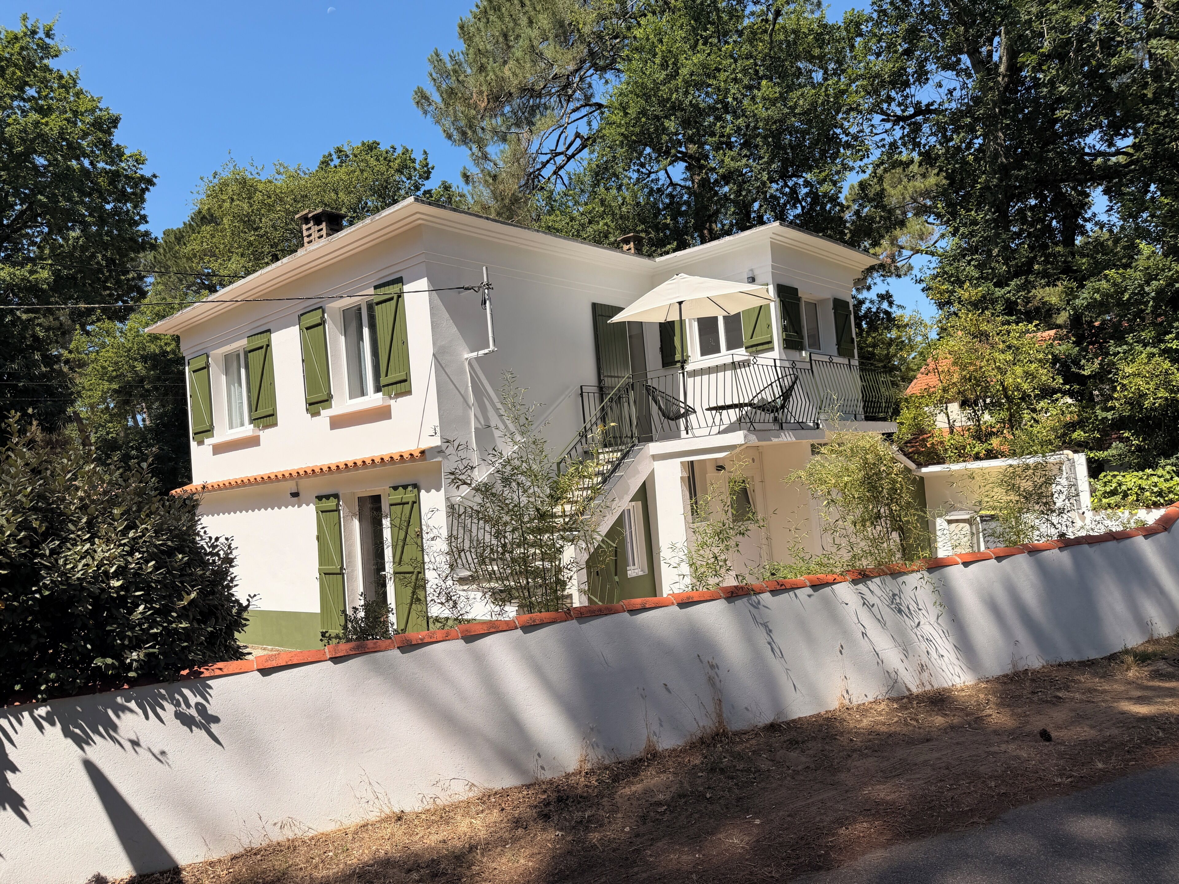 A two-story building with a balcony, a covered outdoor seating area, and a white exterior.