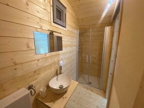 Ein Badezimmer einer Holzhütte mit Waschbecken, Spiegel und Dusche.