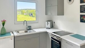 Et køkken med et vindue, kaffemaskine og opvaskemaskine.