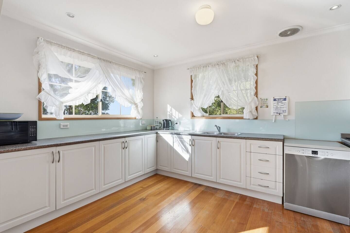 A kitchen with white cabinets, a microwave, a coffee maker, and a dishwasher.