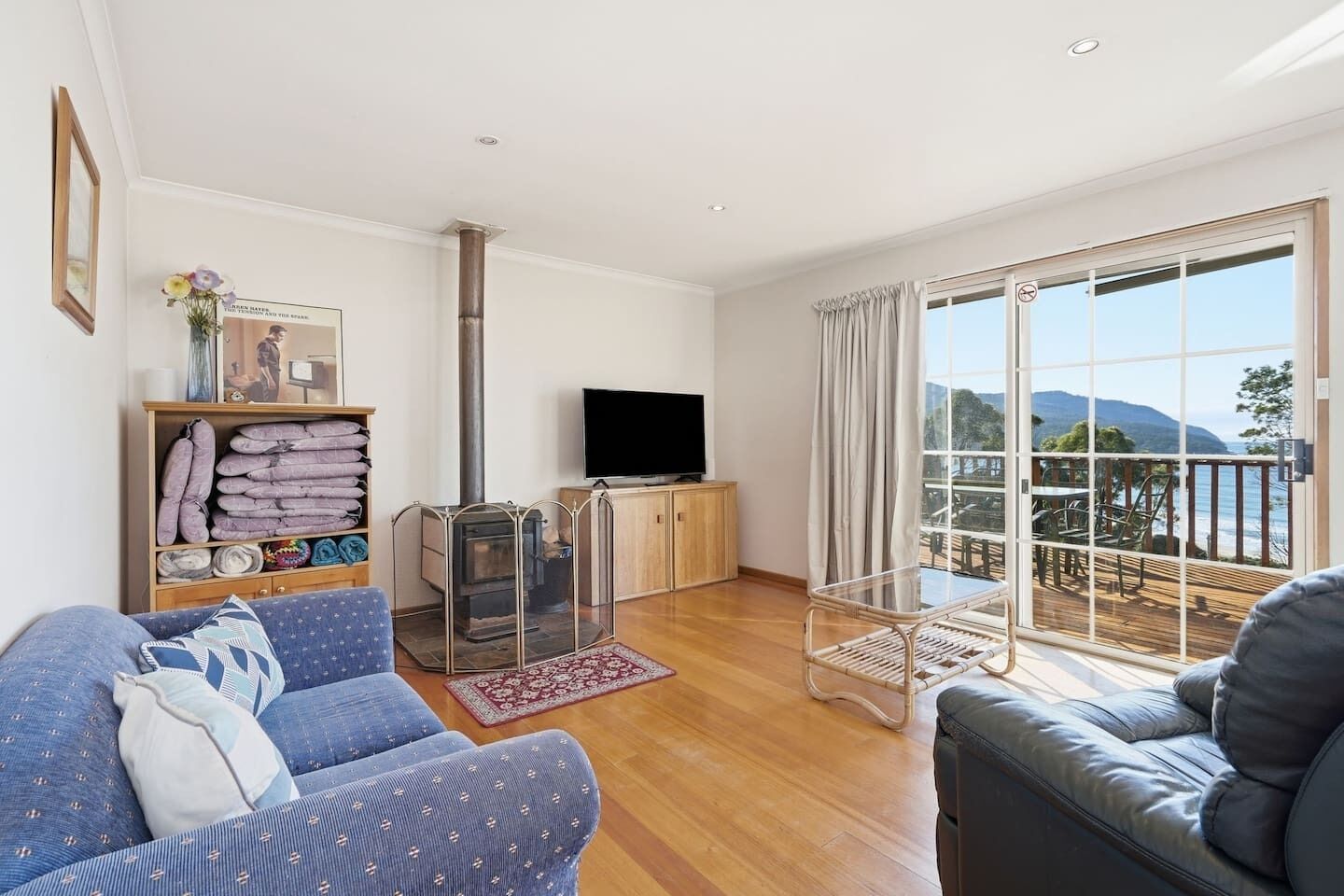 A living room with a sofa, a television, a fireplace, and a balcony with a view.