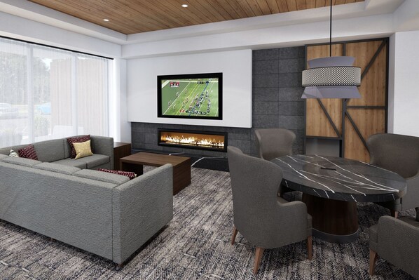 A modern living room with a grey sectional sofa, a coffee table, a fireplace, a TV mounted on the wall, and a dining area with a marble table.