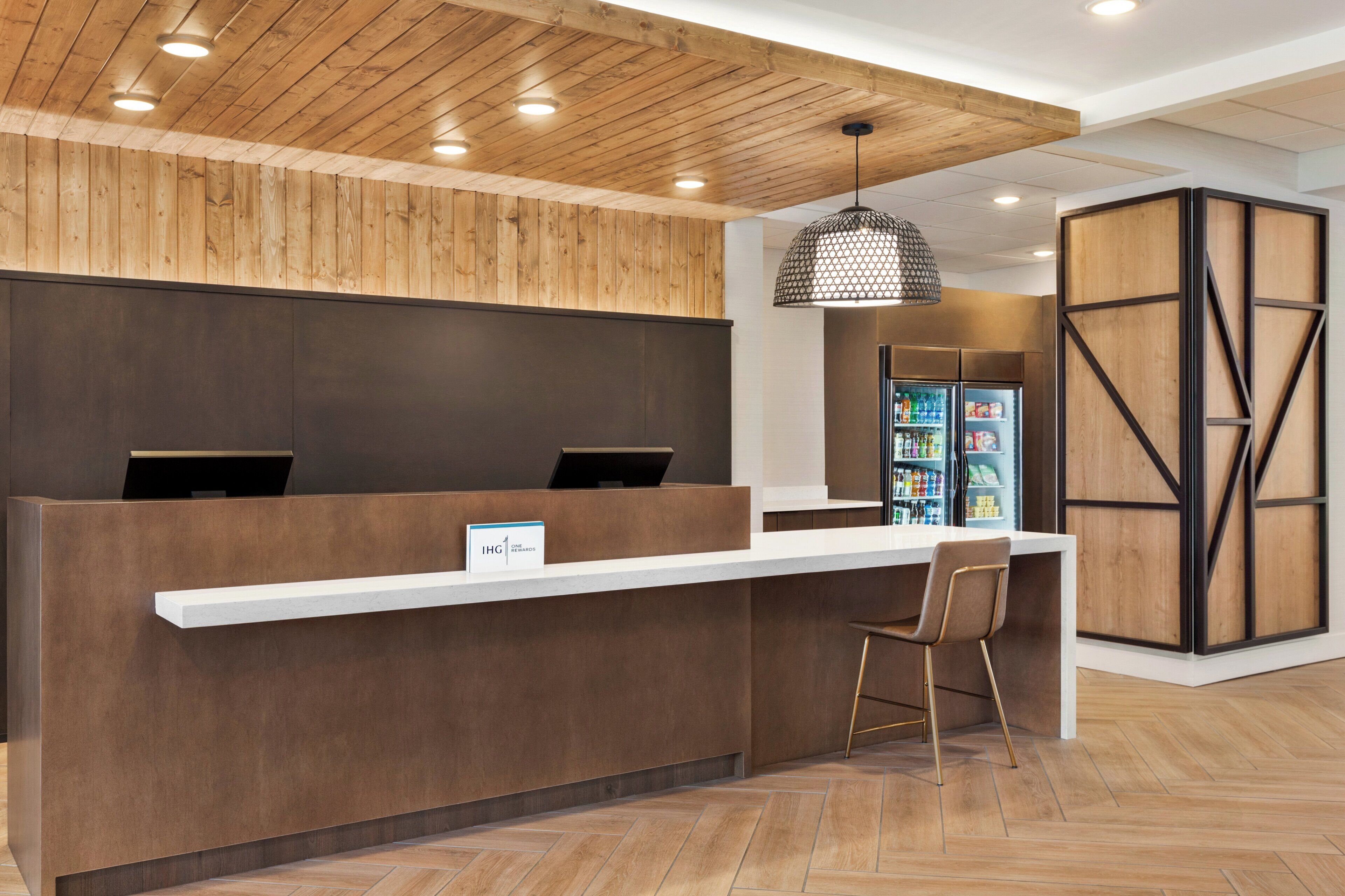 A reception desk with a wooden panel wall, a white counter, and a hanging pendant light.