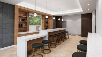 Uma área de bar com bancada branca, prateleiras de madeira e banquetas pretas.
