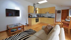 A compact living space with a kitchenette, a flat-screen TV, a sofa, and a dining area.