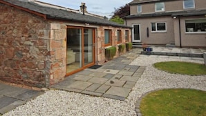 A residential property with a stone building, a modern house, and a paved patio area.