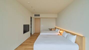 Ein Hotelzimmer mit zwei Betten, einem an der Wand befestigten Fernseher und Holzboden.