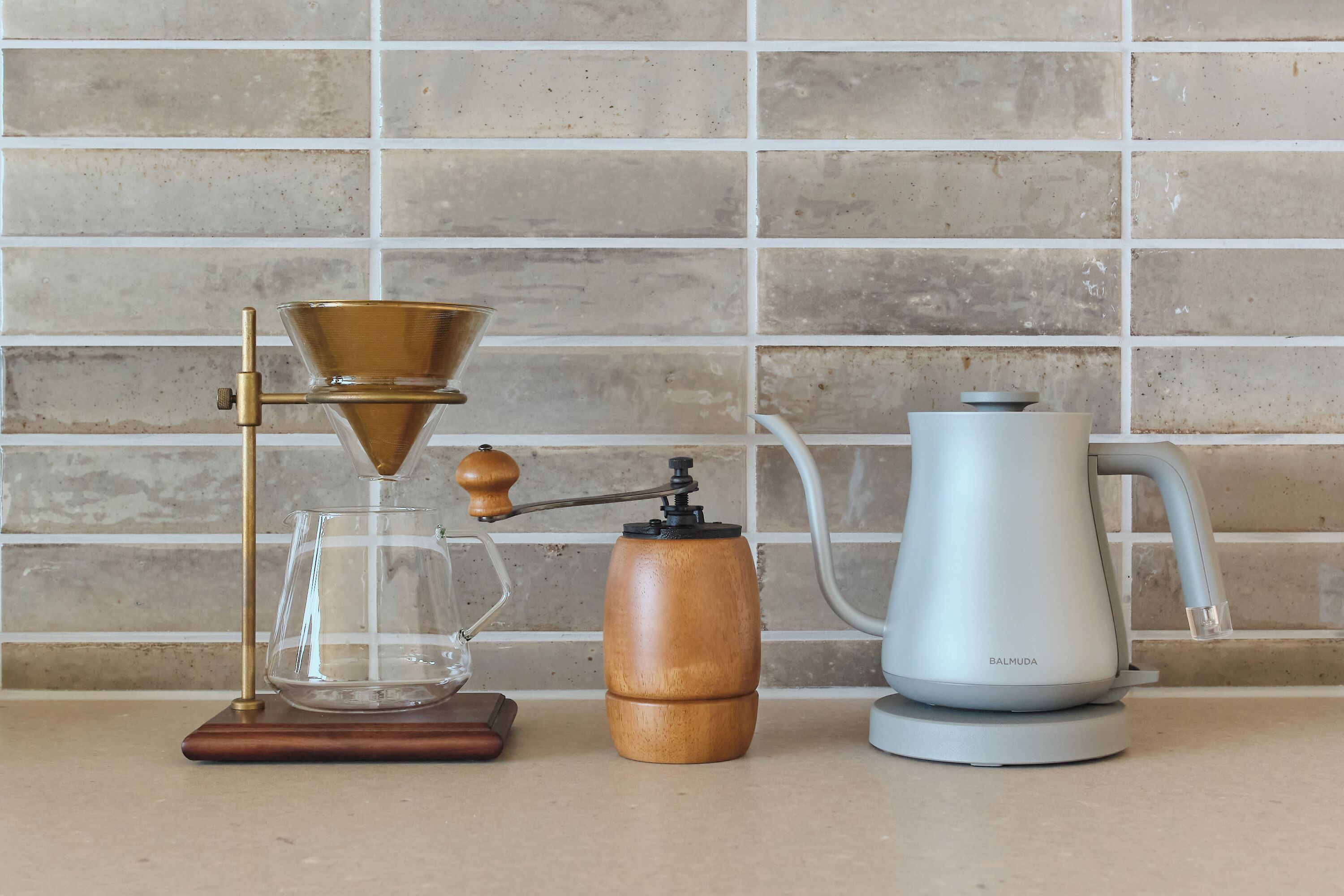 A coffee maker, a grinder, and a kettle on a countertop.