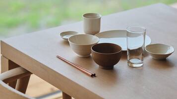 A wooden table with various ceramic bowls and a glass, arranged neatly.