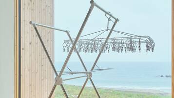A room with a wooden floor, a metal drying rack, and a view of the ocean.