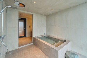 A modern bathroom with a walk-in shower, a bathtub, and a wooden door. - ATUY ISHIZAKI (Hakodate City)