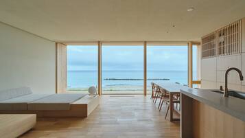 Ein modernes Interieur mit einer Küche, einem Essbereich und einem großen Fenster mit Meerblick.