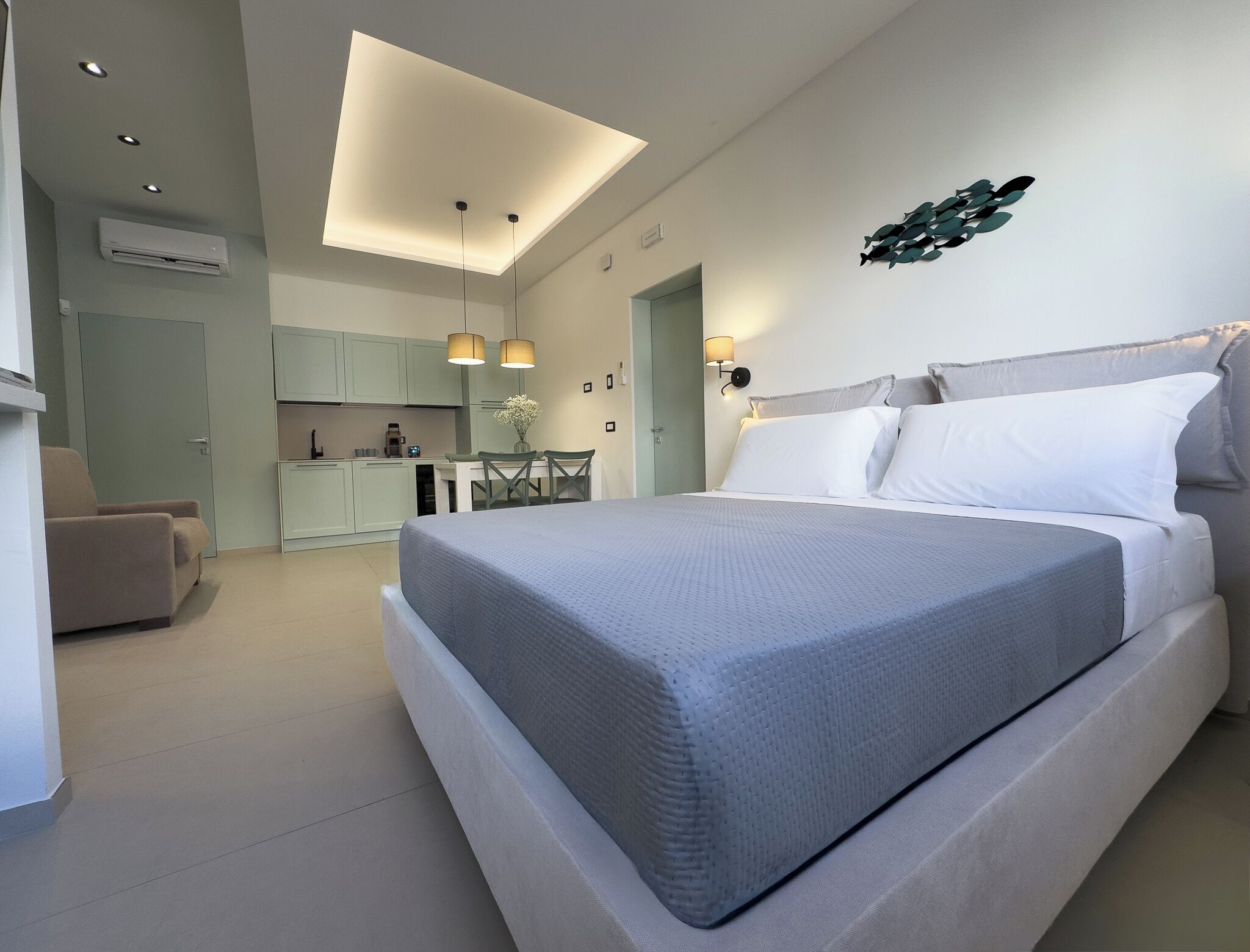 Ein modernes Schlafzimmer mit einem großen Bett, einem Essbereich und einer Küchenzeile.