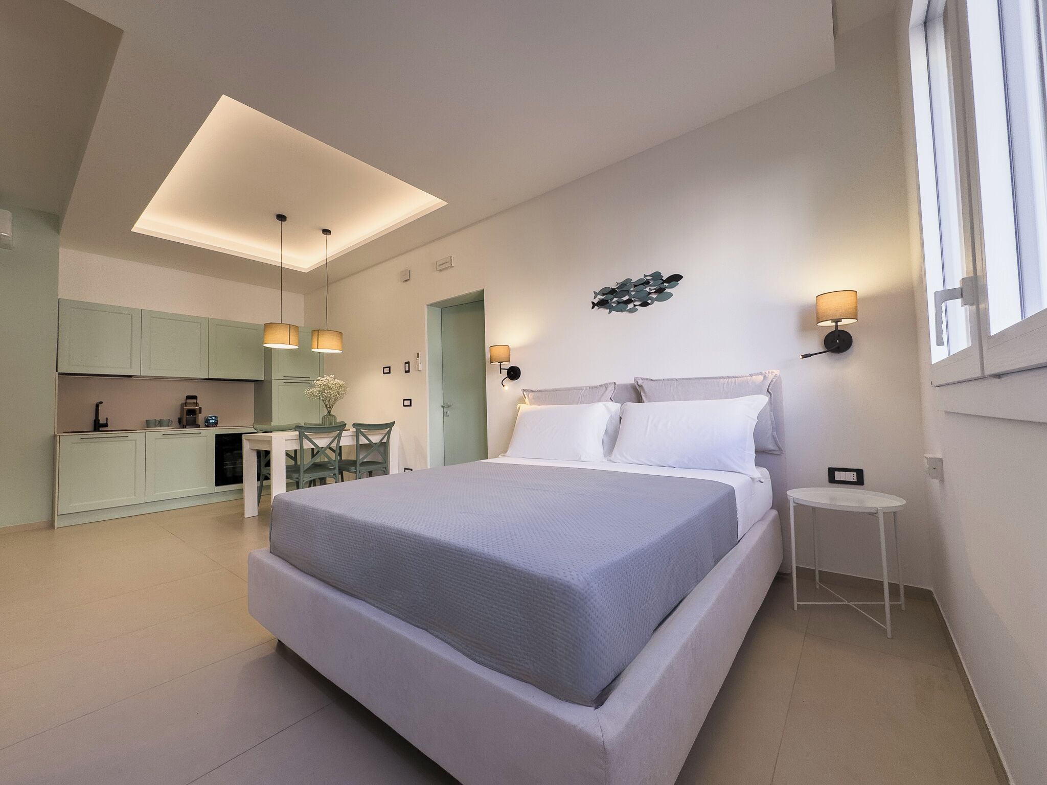 Een moderne slaapkamer met een groot bed, een eethoek en een kitchenette.