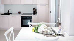 Una cocina moderna con armarios blancos, horno negro y luces colgantes.