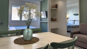 Un comedor con una mesa, sillas, un jarrón con flores e iluminación colgante.