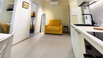 A compact kitchen with a sofa, a dining area, and a small table.