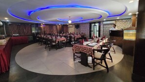 Un restaurant avec des tables rondes, un bar et une scène pour les événements.