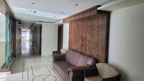 Un couloir avec un canapé en cuir marron, un fauteuil et un mur à texture.
