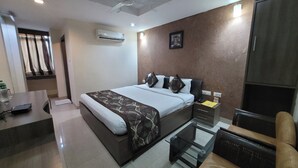 Une chambre d’hôtel équipée d’un lit, d’une table de chevet, d’une chaise, d’un bureau et d’un ventilateur de plafond.
