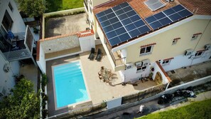 A residential property with a swimming pool, solar panels, and a covered patio.